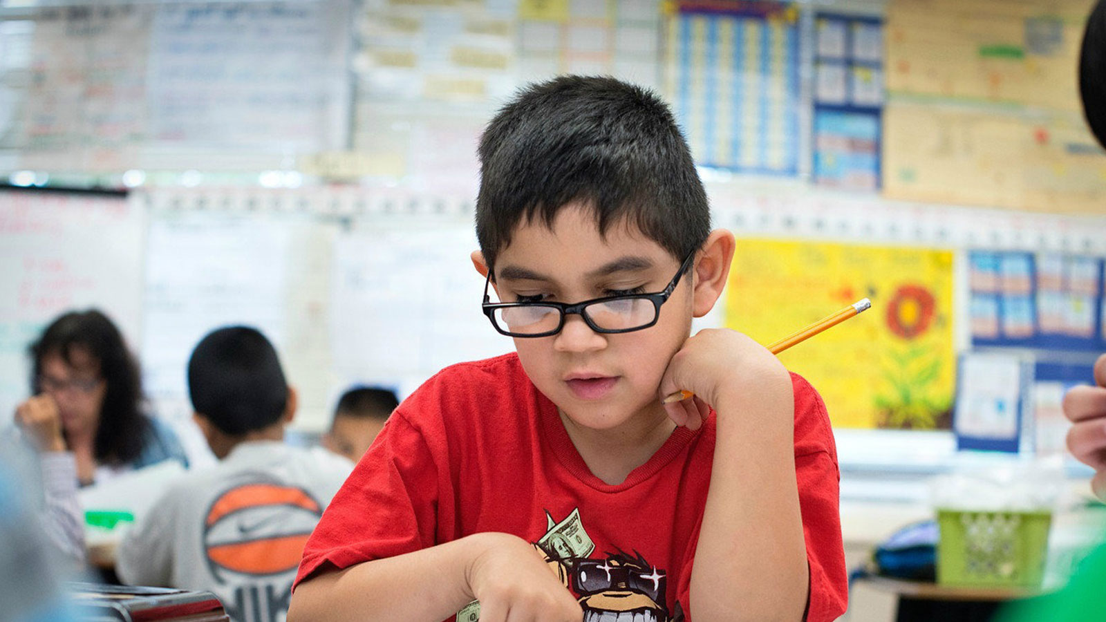 A young student in a red shirt works on an assessment that will give his teacher important data
