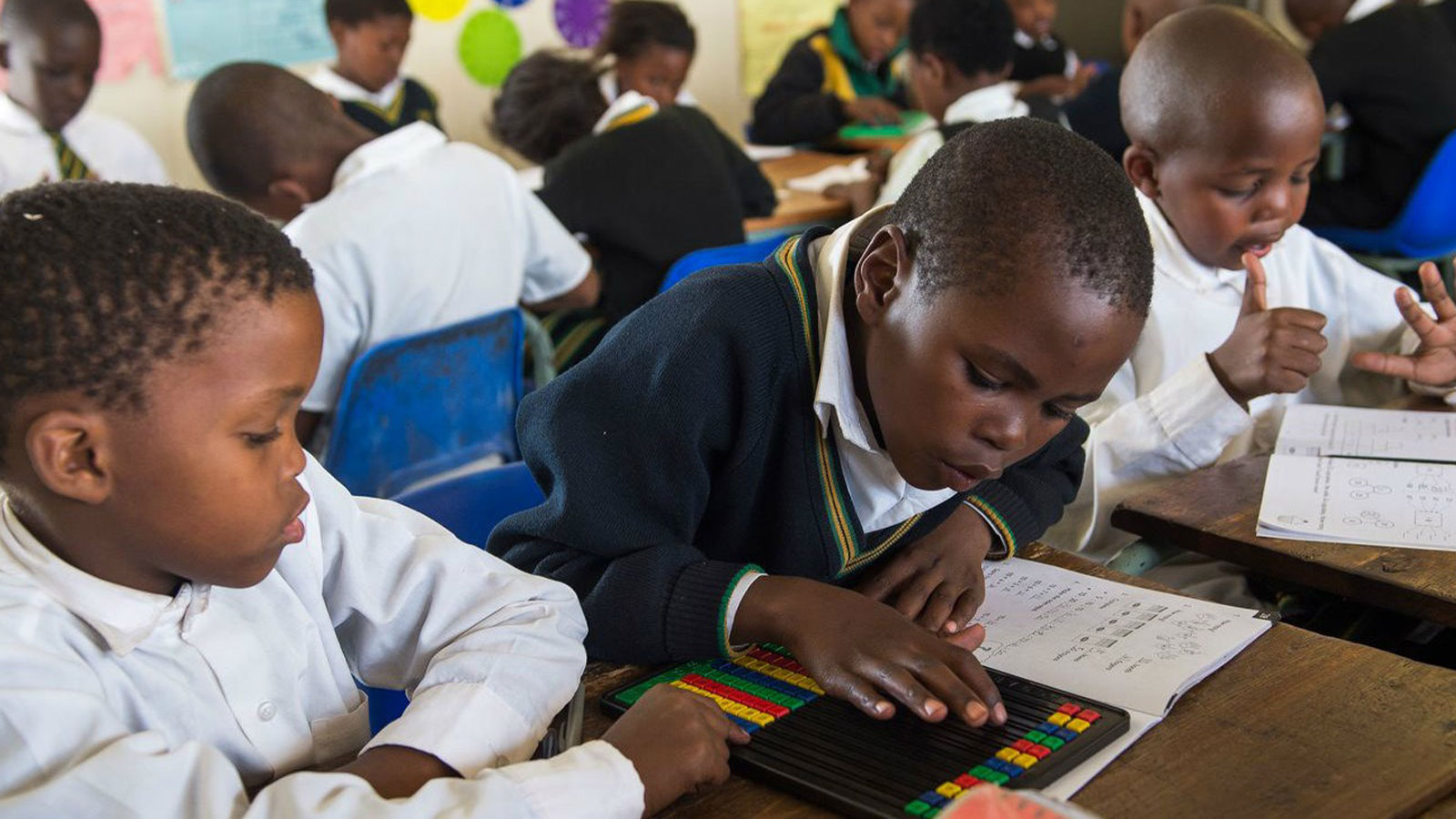 Three children impacted by the Michael & Susan Dell Foundation read together in a classroom