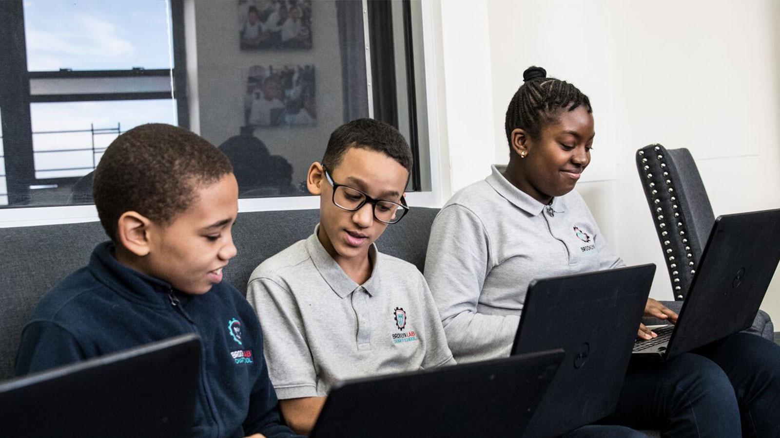 Three students work on an assignment together on their computers