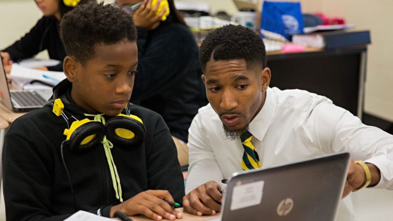 A student completes an assignment with the help of a teacher