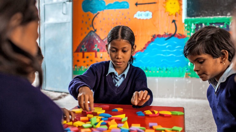 A group of young students play a game in a classroom in India