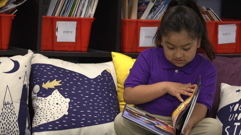 A young student reading in a classroom