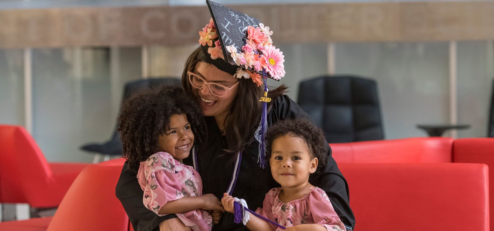 A mom in cap and gown at graduation with her two children