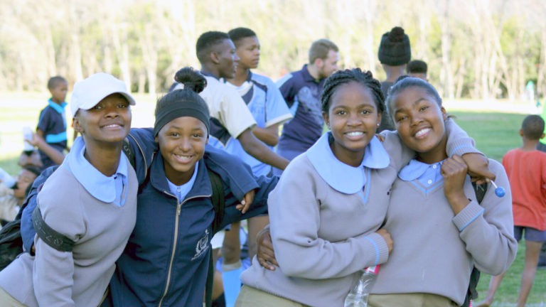 Smiling female students gather outside with other South African students in Bonnievale.