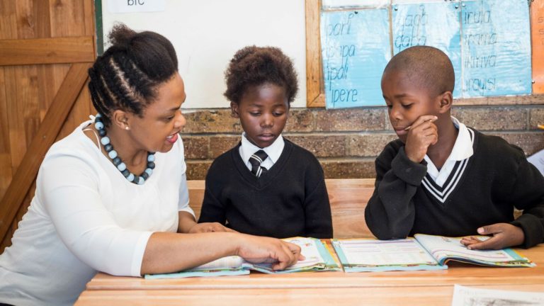 A reading teacher uses Funda Wande workbooks to teach South African students to read.