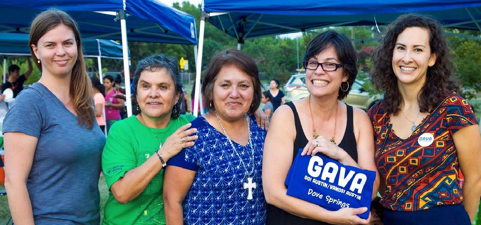 Five women stand together; one is holding up a GAVA sign