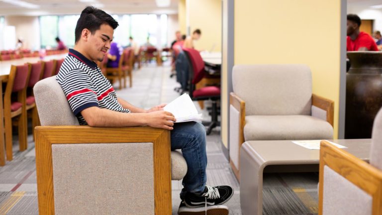 A student reads a book in a library