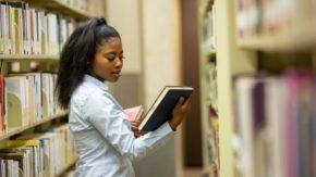 A college student looks over a book in a library