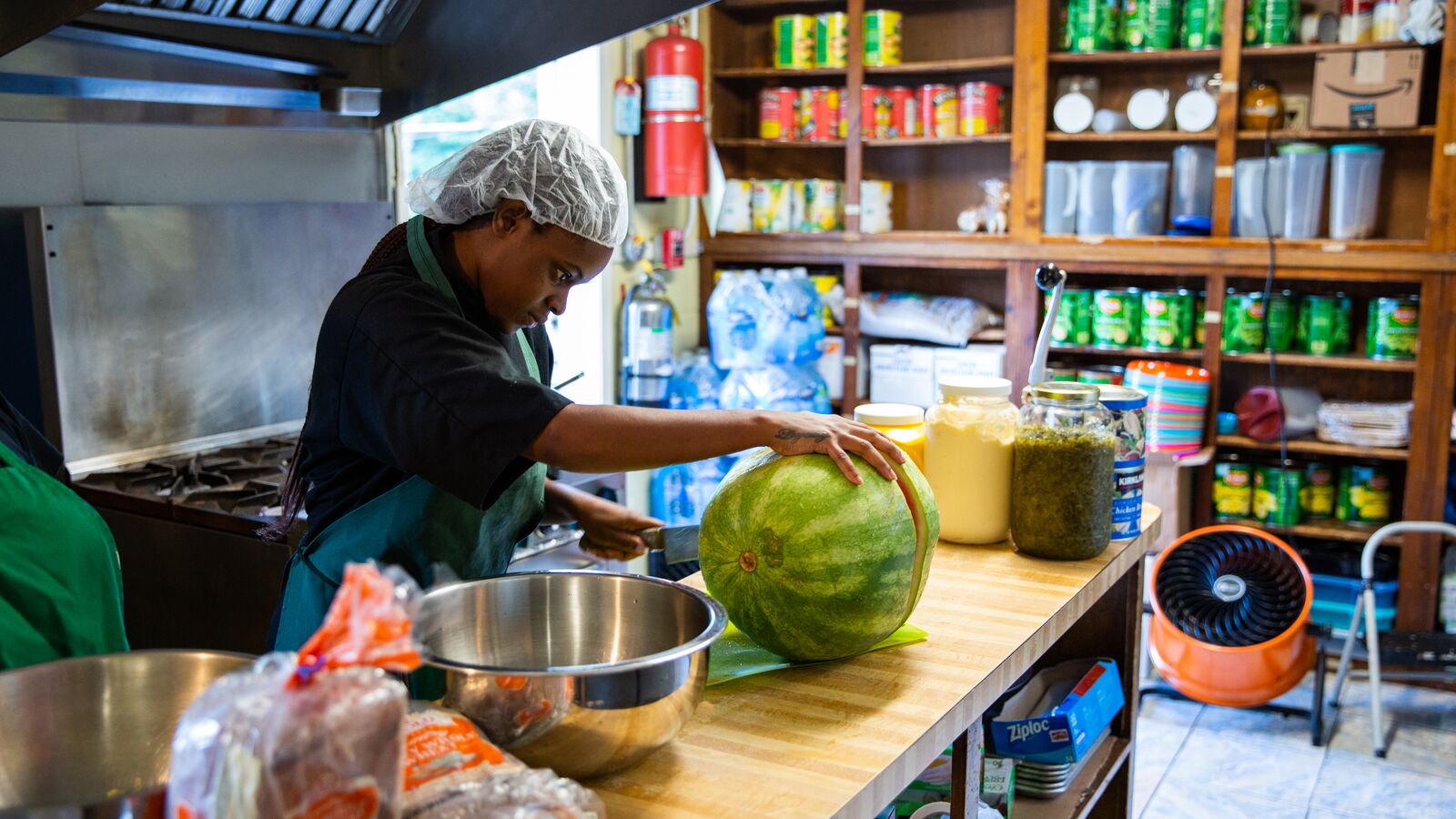 A food service worker prepares fresh, healthy fruit for children in a school