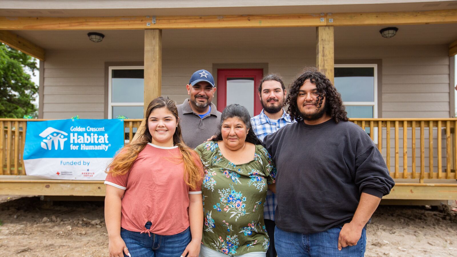 Alice Silvas, her granddaughter Clarissa, and their family in front of their home built by Golden Crescent Habitat for Humanity.