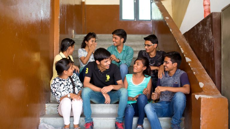 Students in a school in India talk together while sitting on stairs
