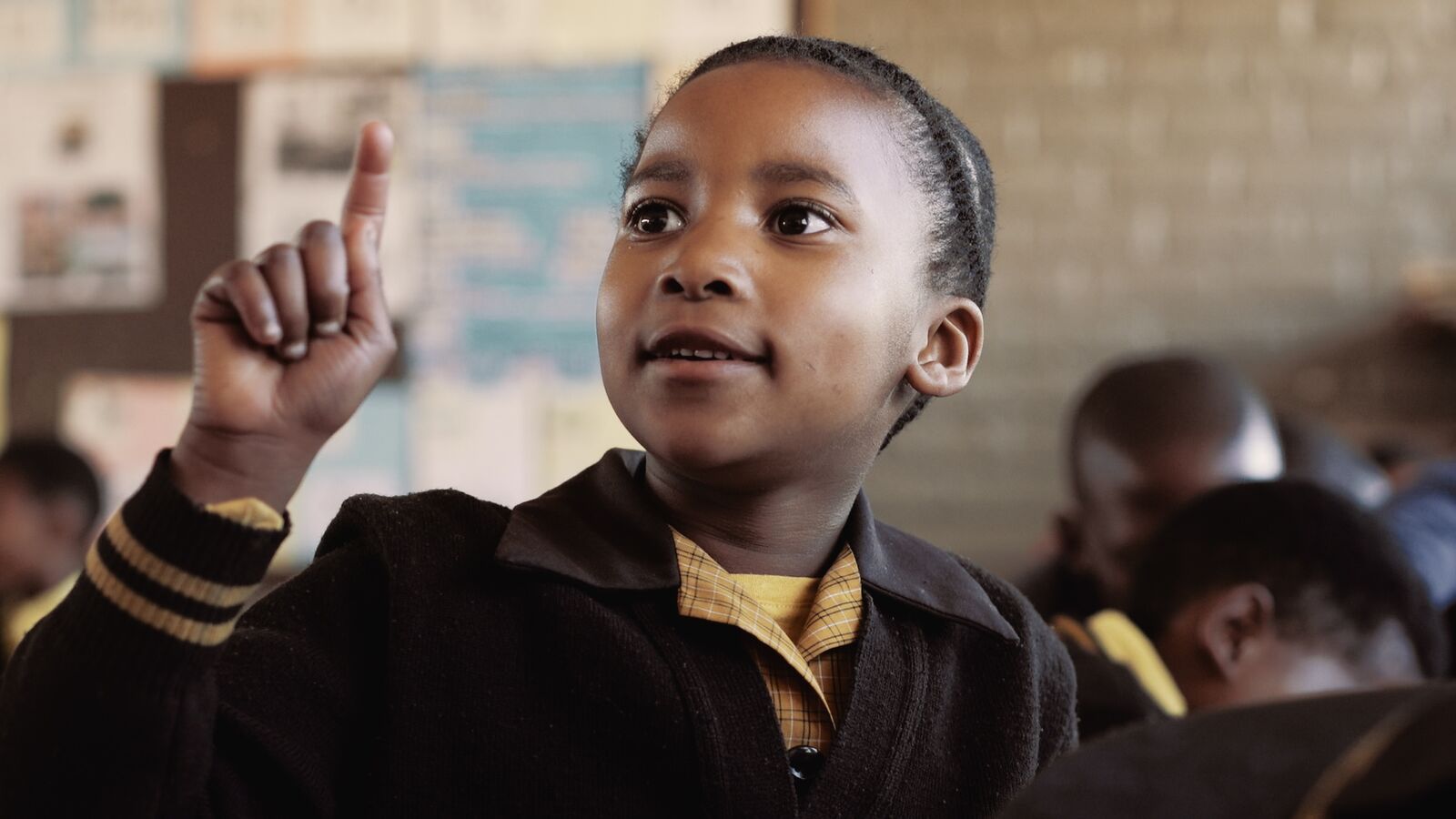A student in a classroom in South Africa raises her hand