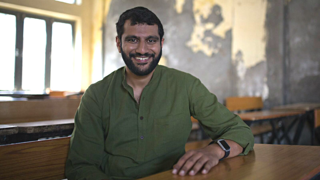 Akshay Saxena of Avanti Learning Centres smiles at a desk in India
