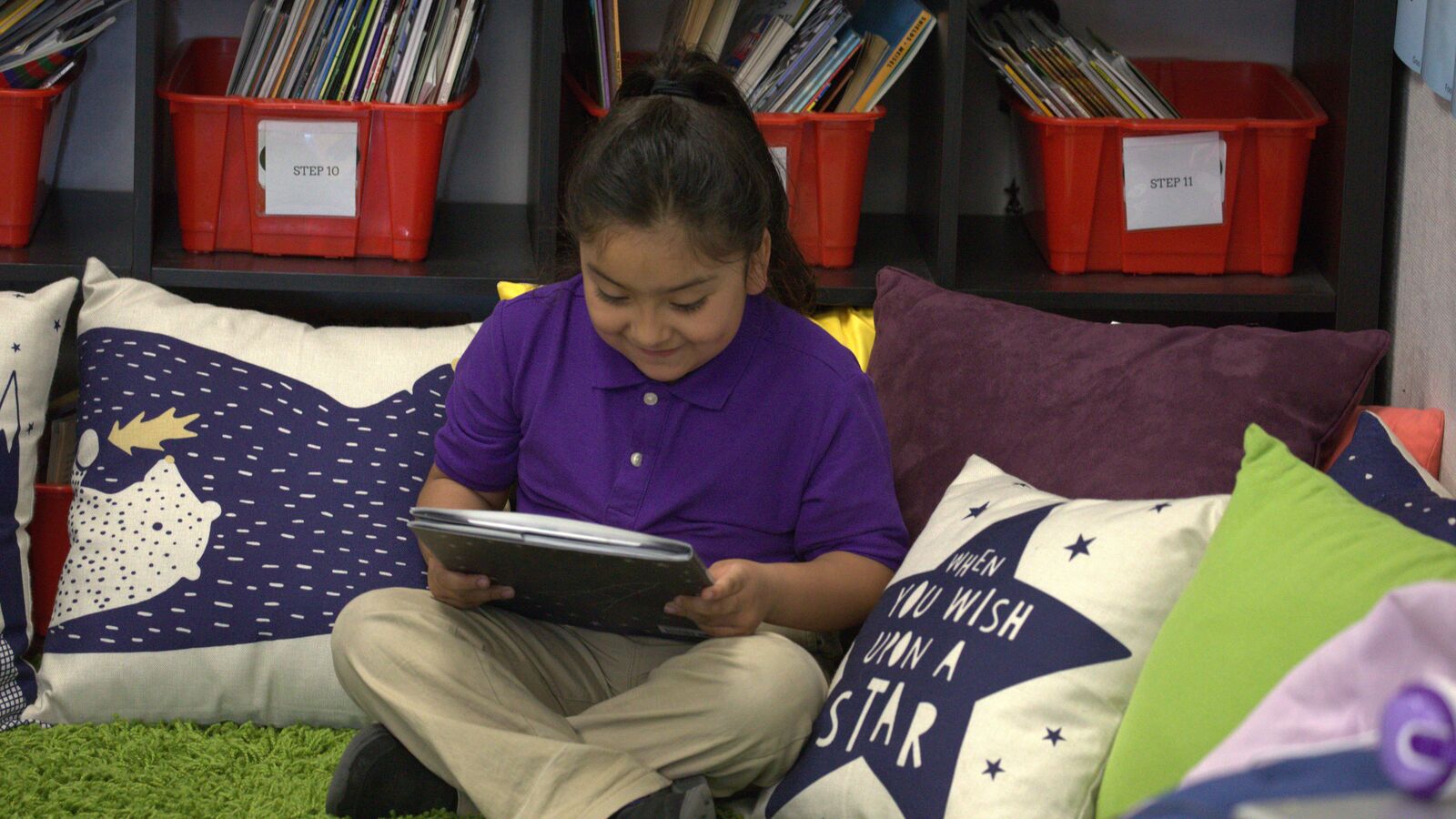An elementary school student reads a book in class