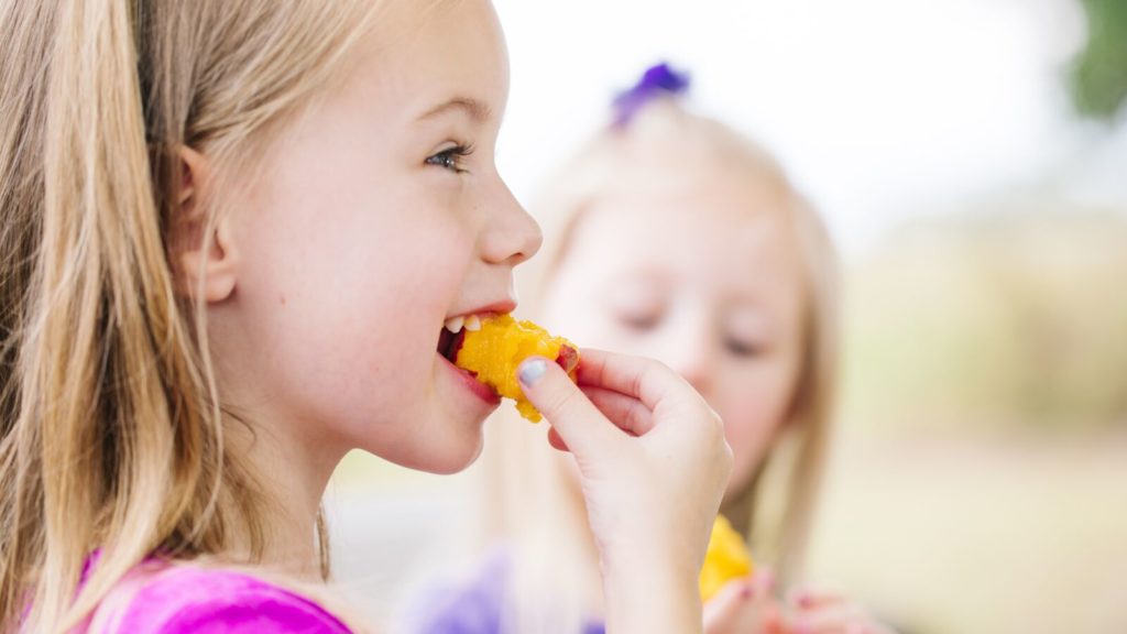 A young girl eats a peach purchased from a farmer's market in Austin, Texas