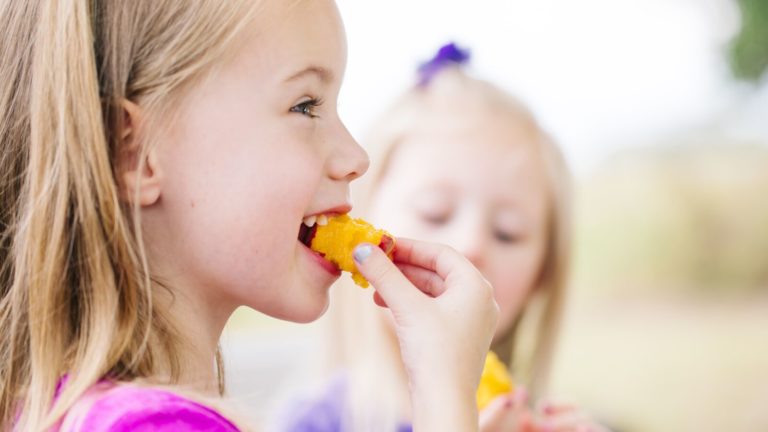 A young girl eats a peach purchased from a farmer's market in Austin, Texas