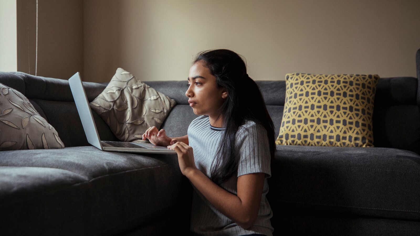 A female college student uses her computer in her home while quarantined.