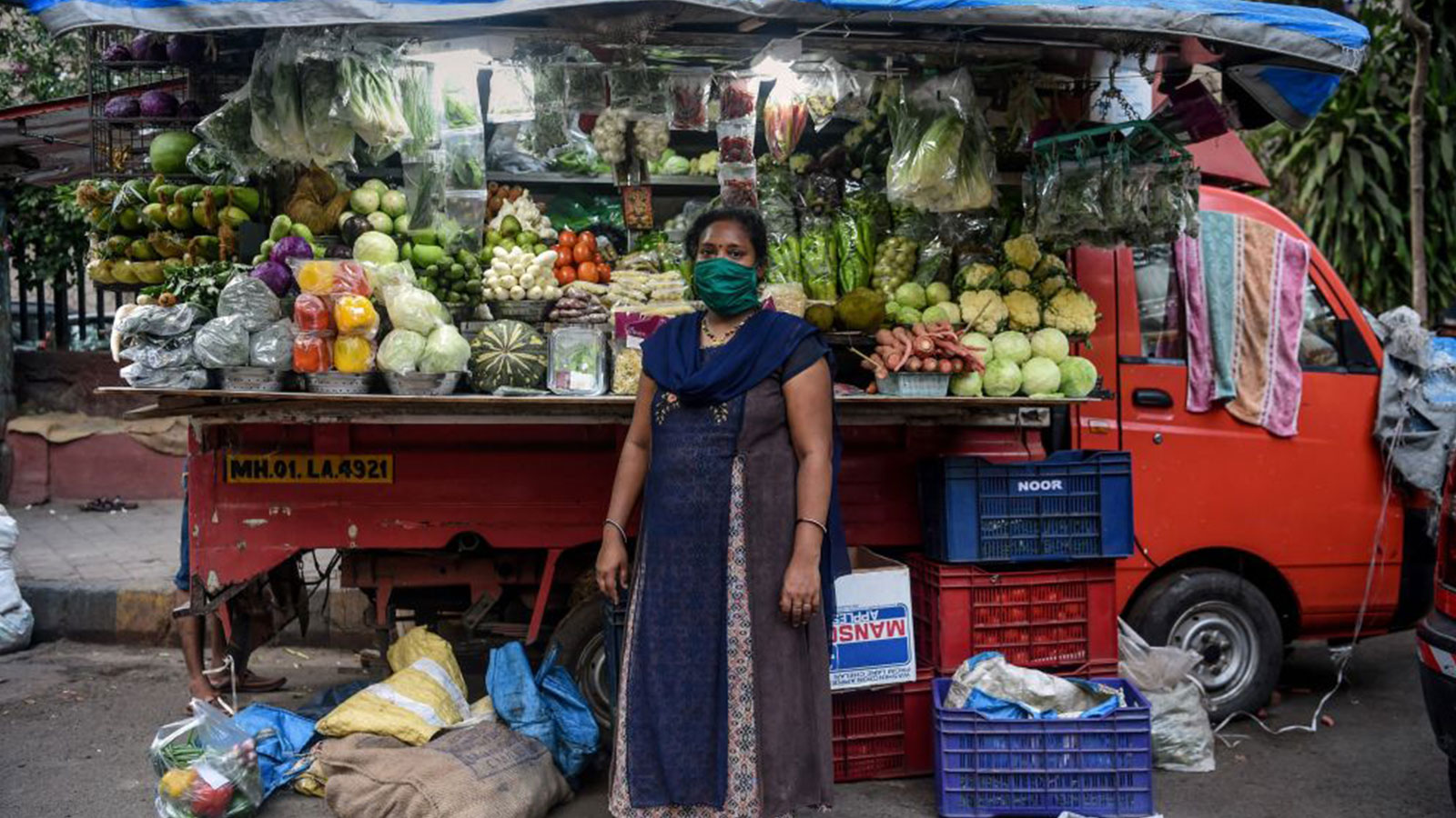 A gig worker in India stands in front of a fruit stand