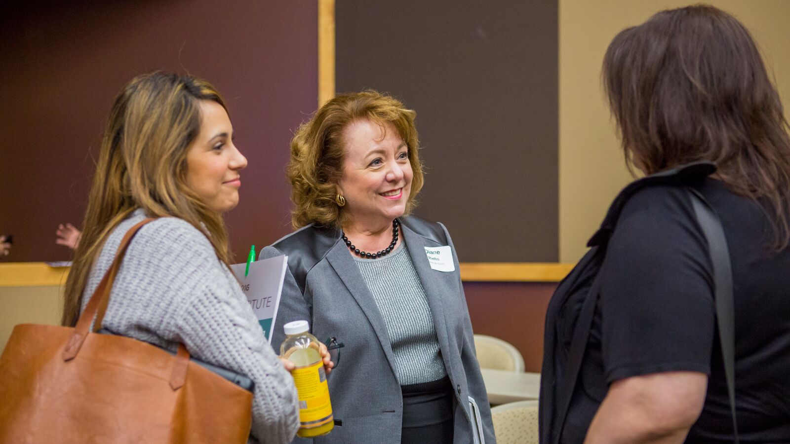 Three women stand together in discussion