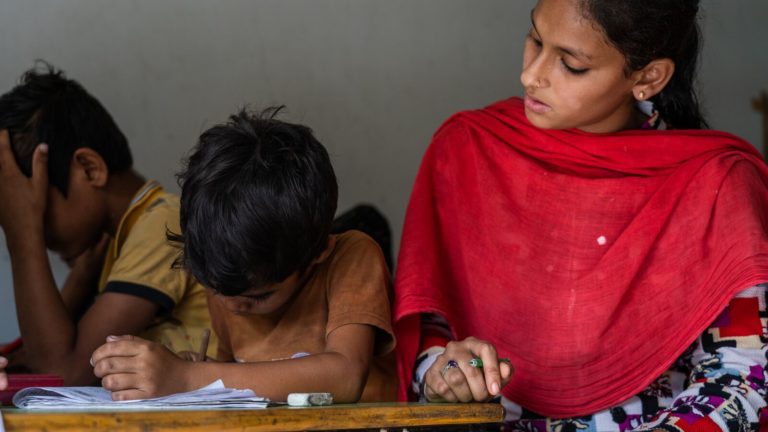 Students work with a teacher in India