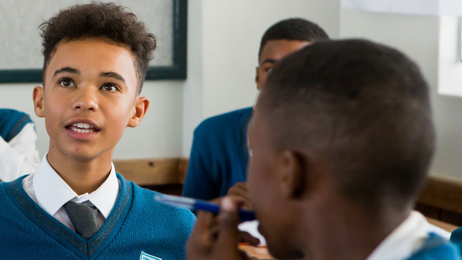 Students from Apex High School, a no-fee public school supported by Acorn Education, talk in a group in a classroom.