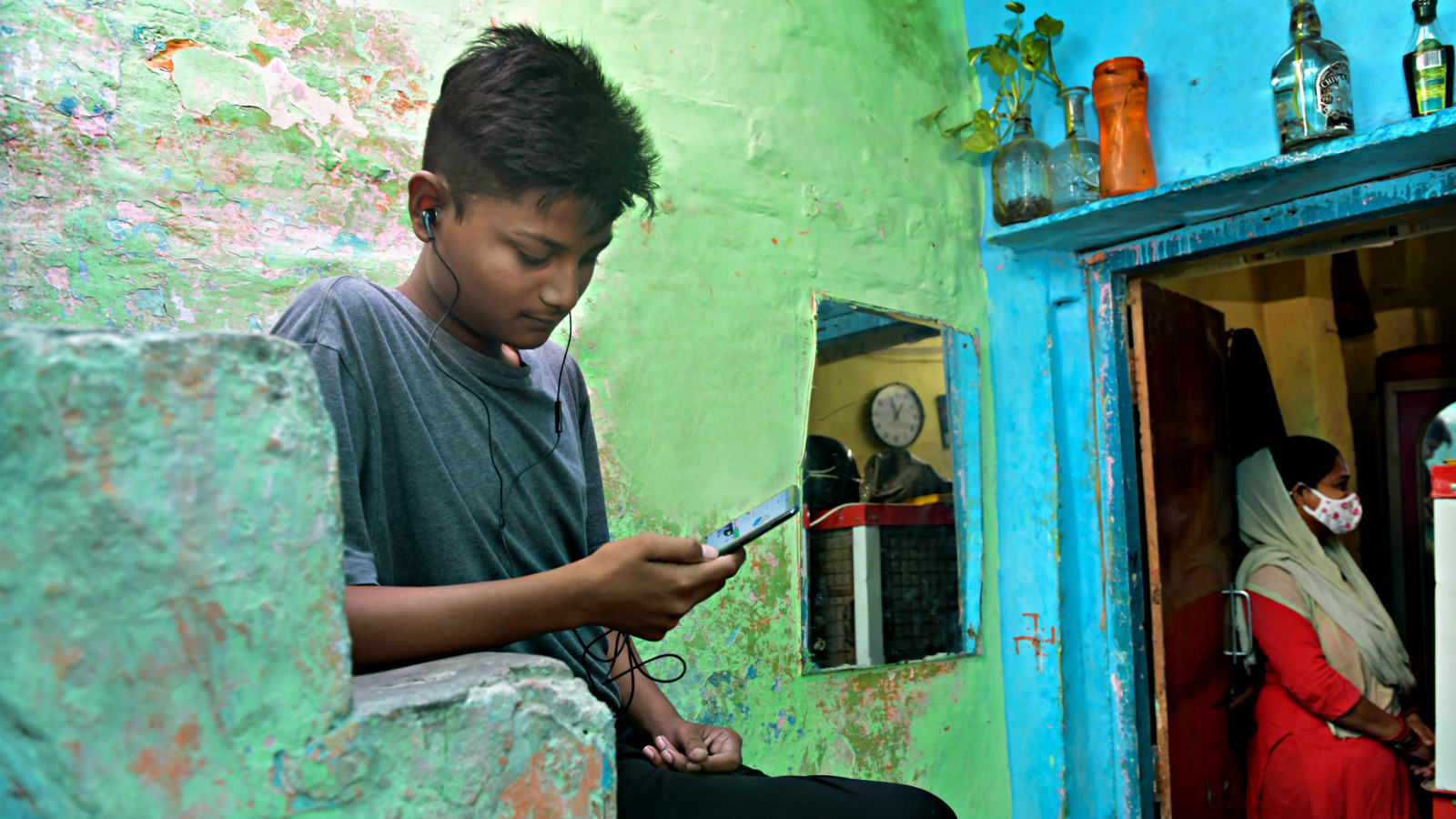 A young man in India uses the enguru app on his phone to learn English