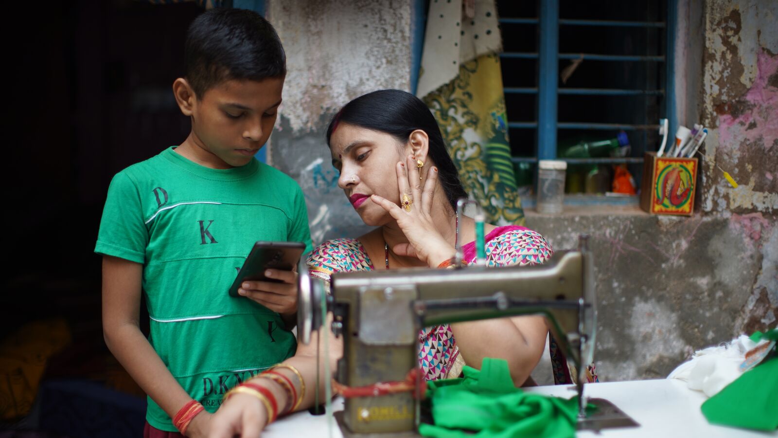 A mother in India helps her son access ConveGenius technology on his device.