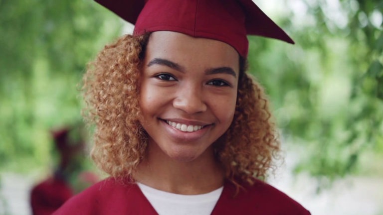A student supported by Strive for College stands in her graduation cap