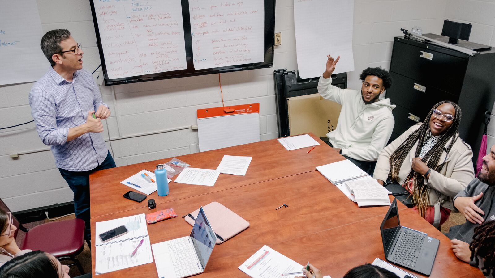 Group of Braven fellows convening in Learning Labs sitting around a table in discssion with their instructor.