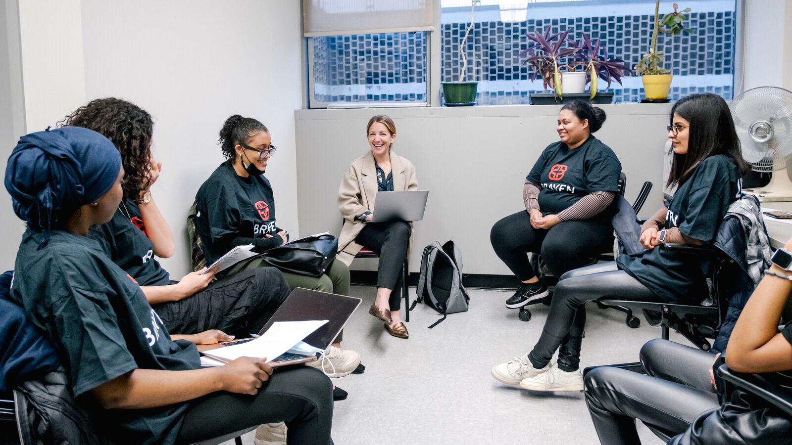 Group of Braven fellows convening in Learning Labs sitting together in a circle discussing their project.