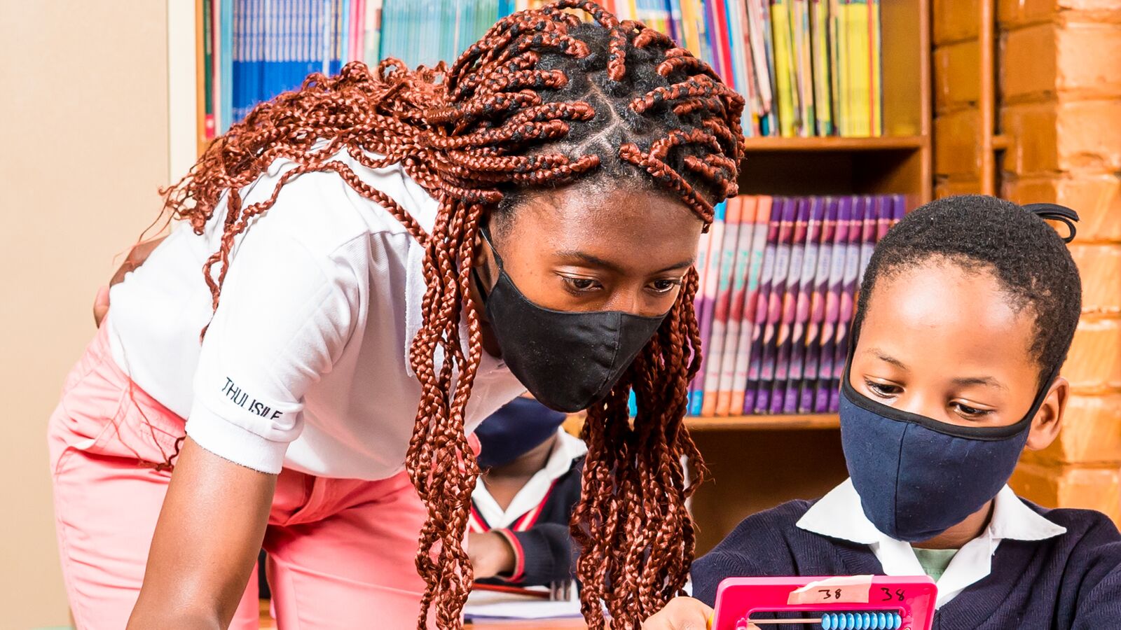 A JumpStart intern helps a student in a South African classroom.