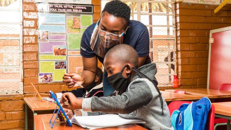 A JumpStart intern helps a student in a South African classroom.