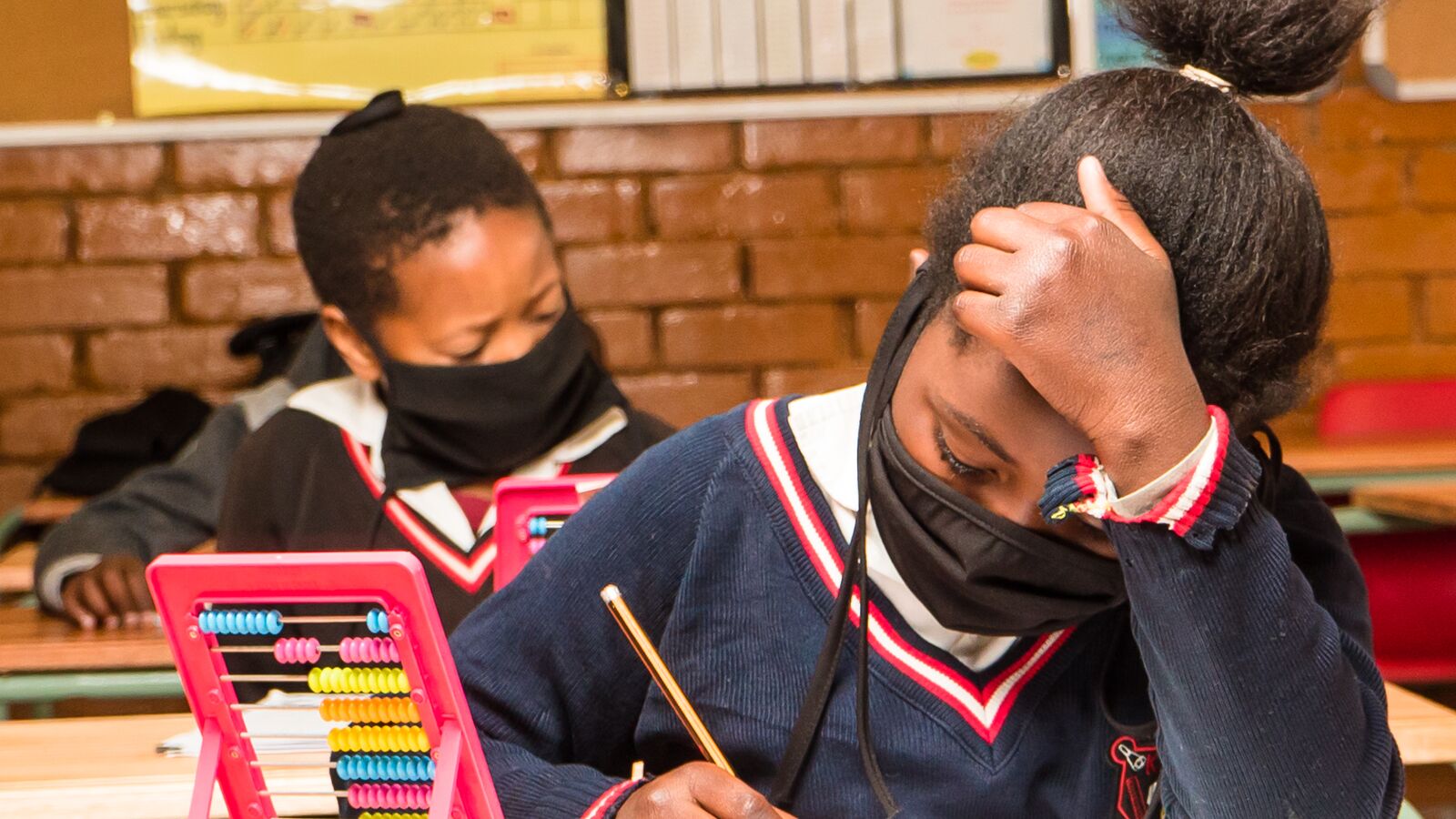 A JumpStart intern helps a student in a South African classroom.
