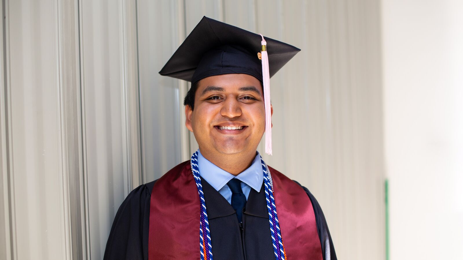 A Dell Scholars student stands in his cap and gown on graduation day