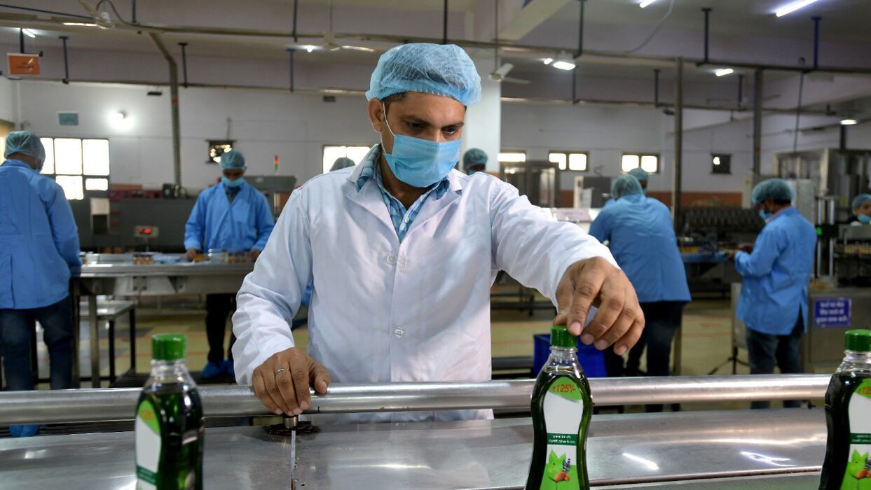 A gig worker in India puts a cap on a product in a factory setting