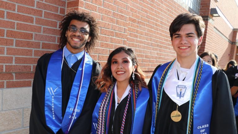 Spring Branch ISD students stand together wearing their graduation caps and gowns.
