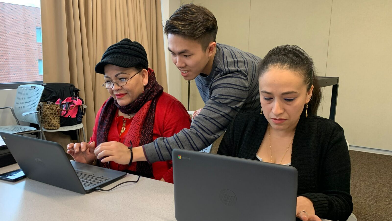 Two people in Boston work on computers to gain digital skills through Tech Goes Home