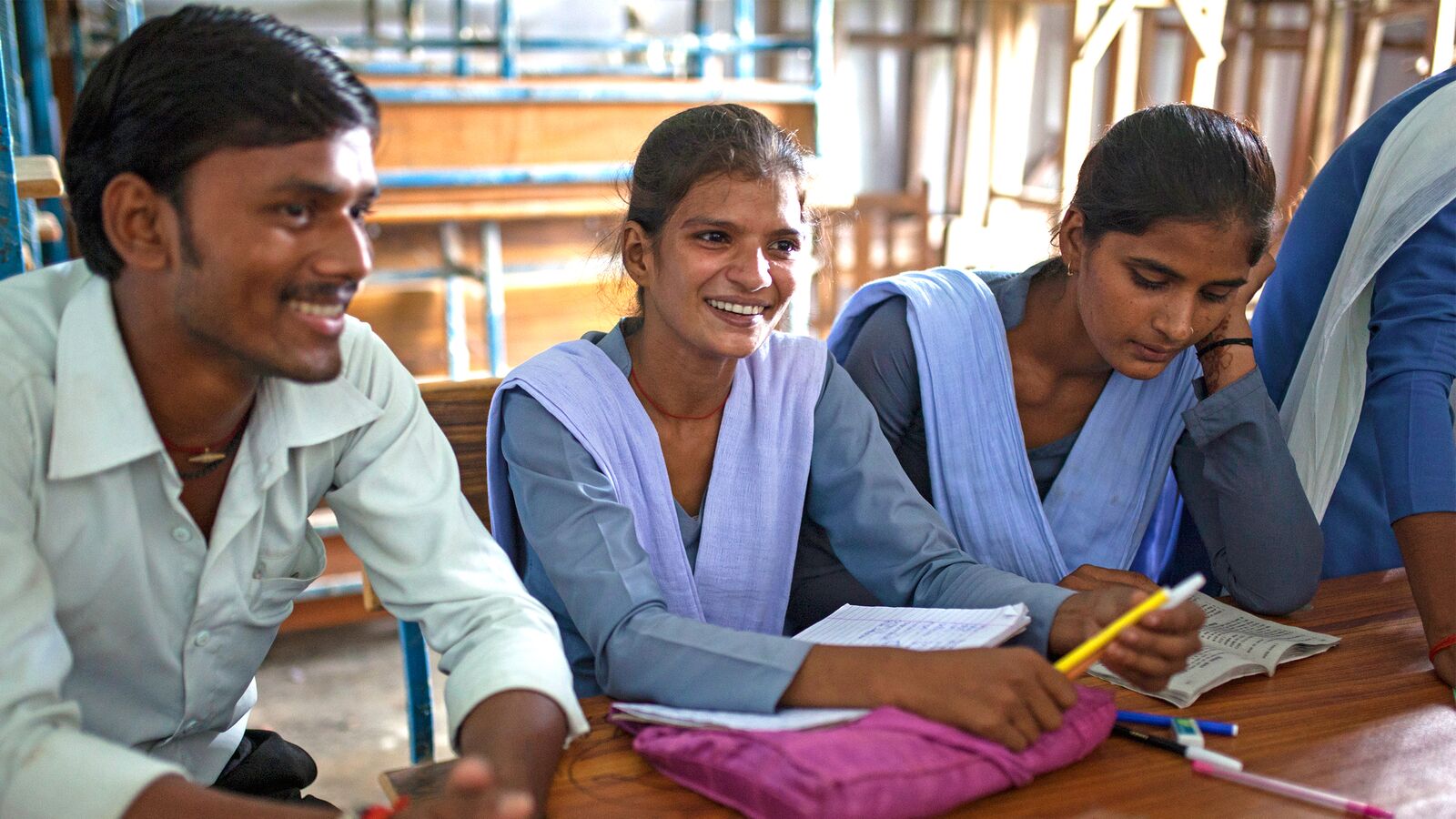 Three students in India sit together at a des