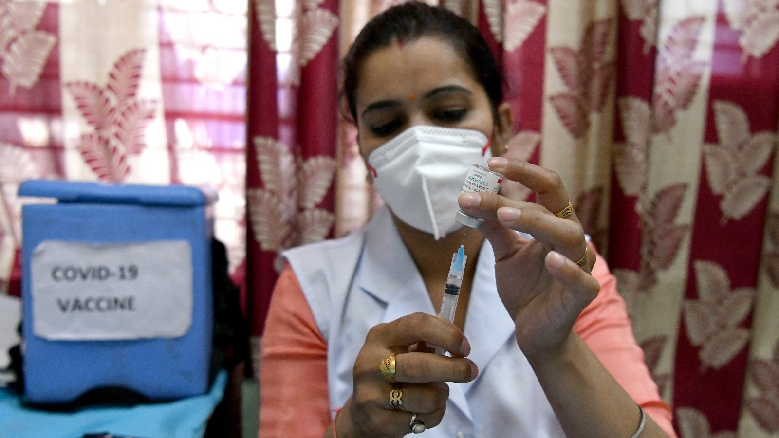 A healthcare worker in India holds a COVID-19 vaccine.
