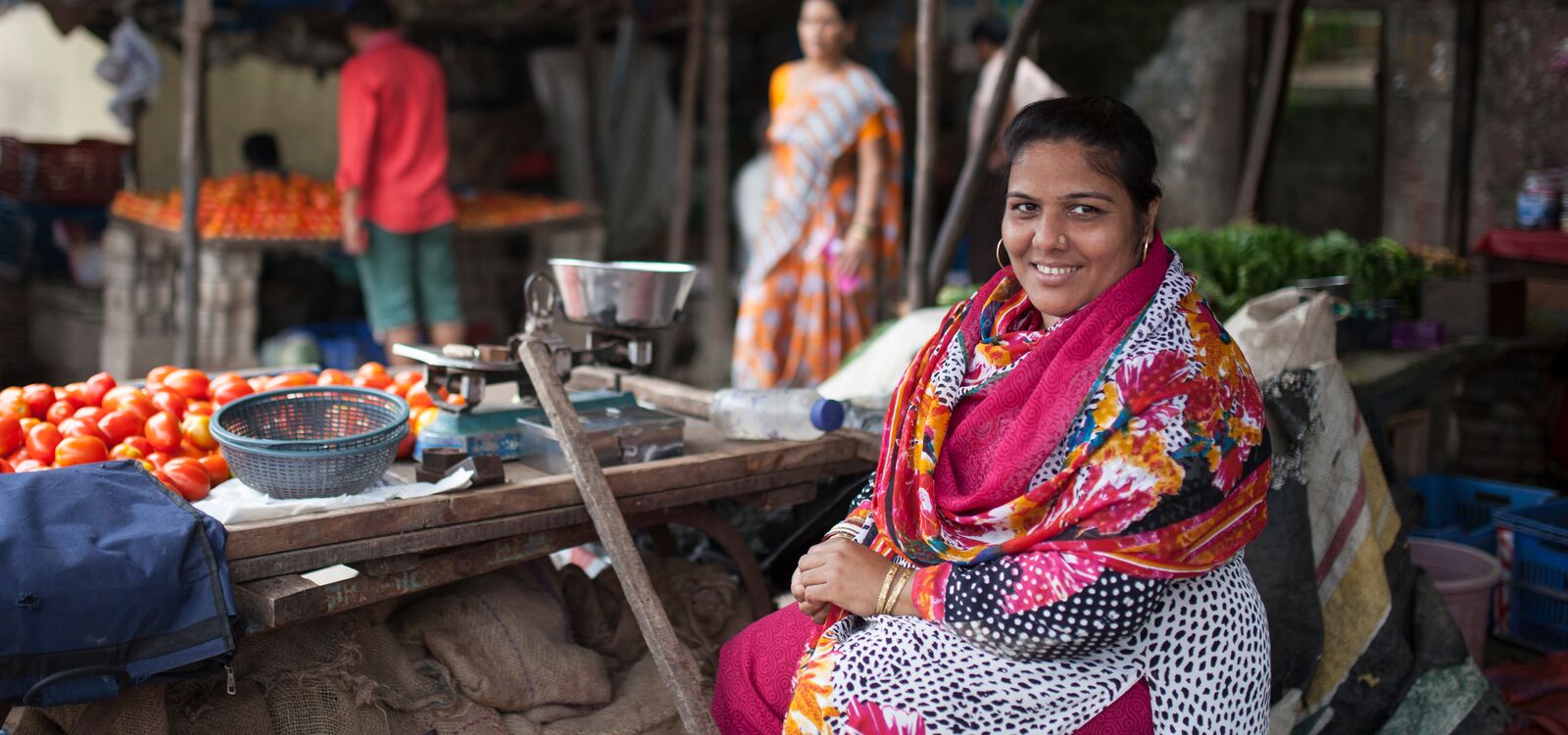 A woman in India sits behind her vegetable stall