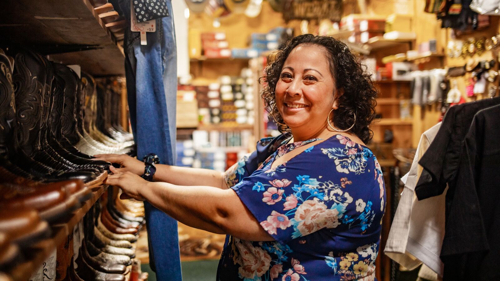 A small business owner stands in front of cowboy boots in her store