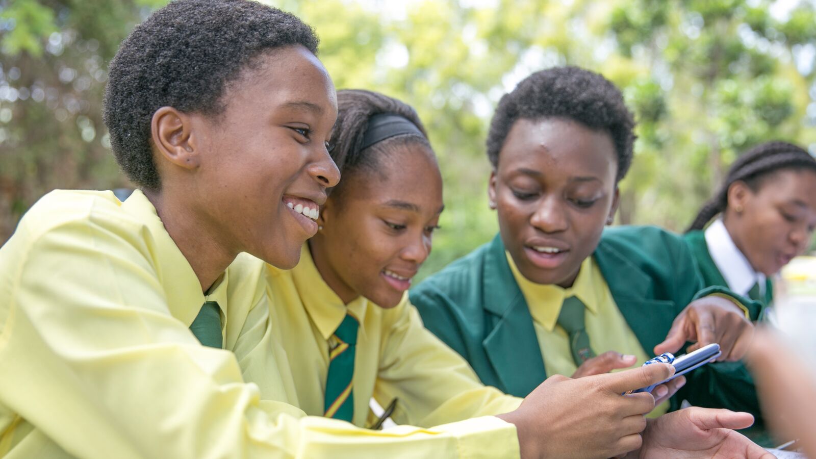 Three South African students work on Siyuvula math assignments using a phone