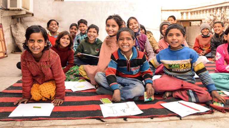 Students in India do schoolwork on a blanket