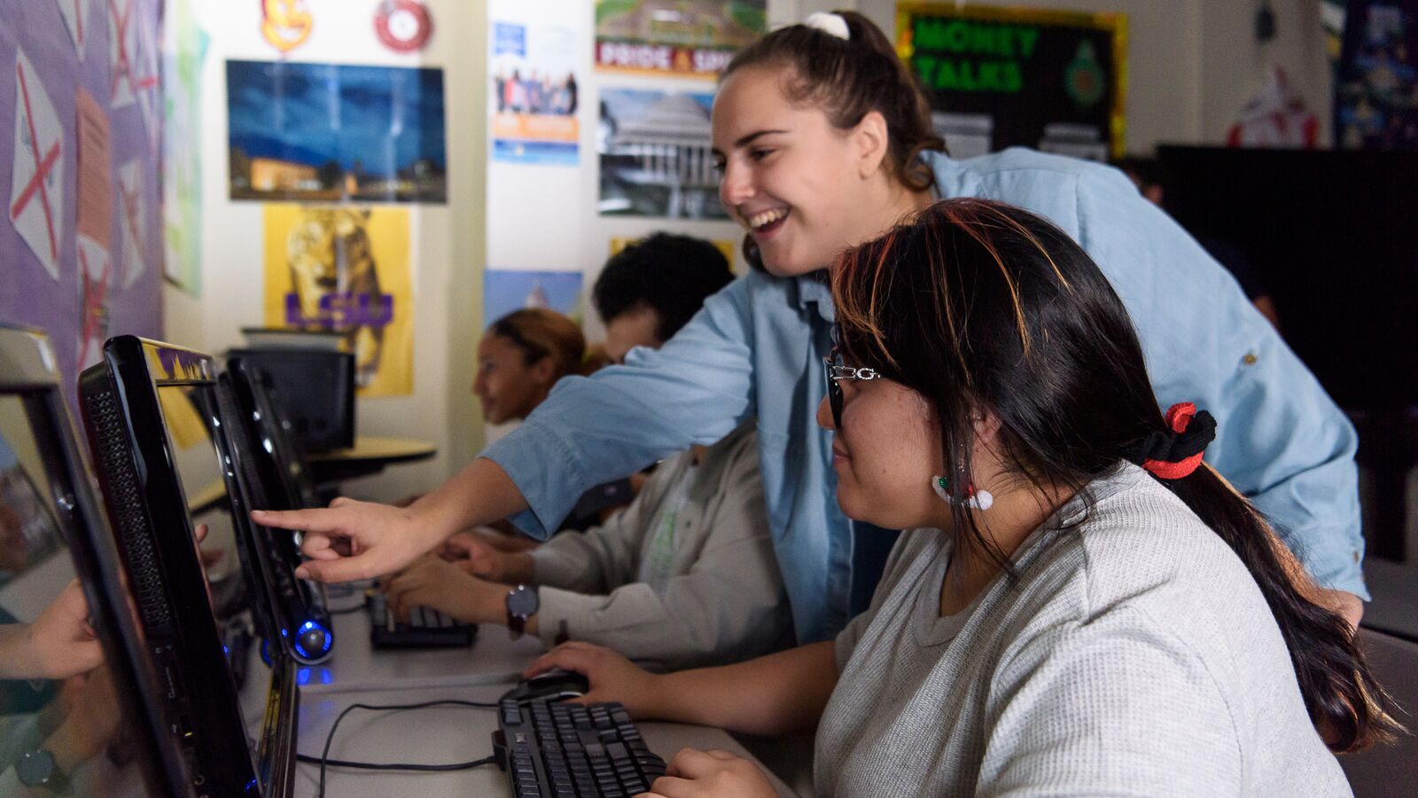 A student works on the computer as a mentor points something out on the screen