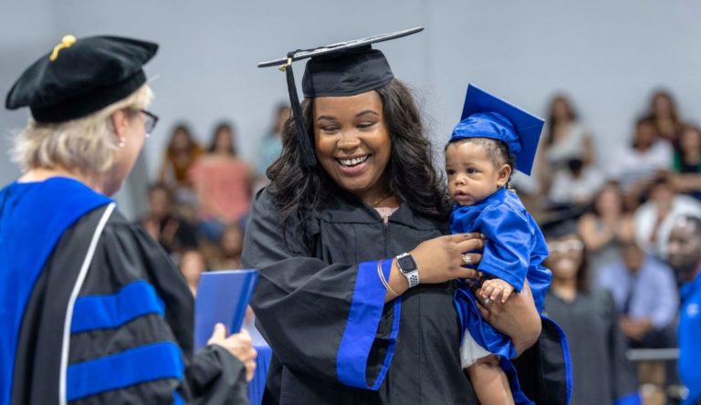 Mother crosses the graduation stage with her child in hand