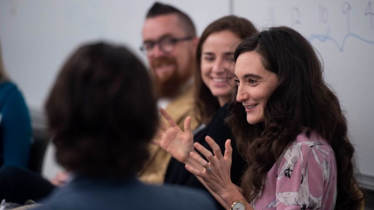 A female smiles while presenting to a group of people