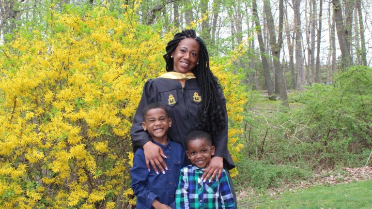 A college graduate supported by Generation Hope poses in cap and gown with her two sons.
