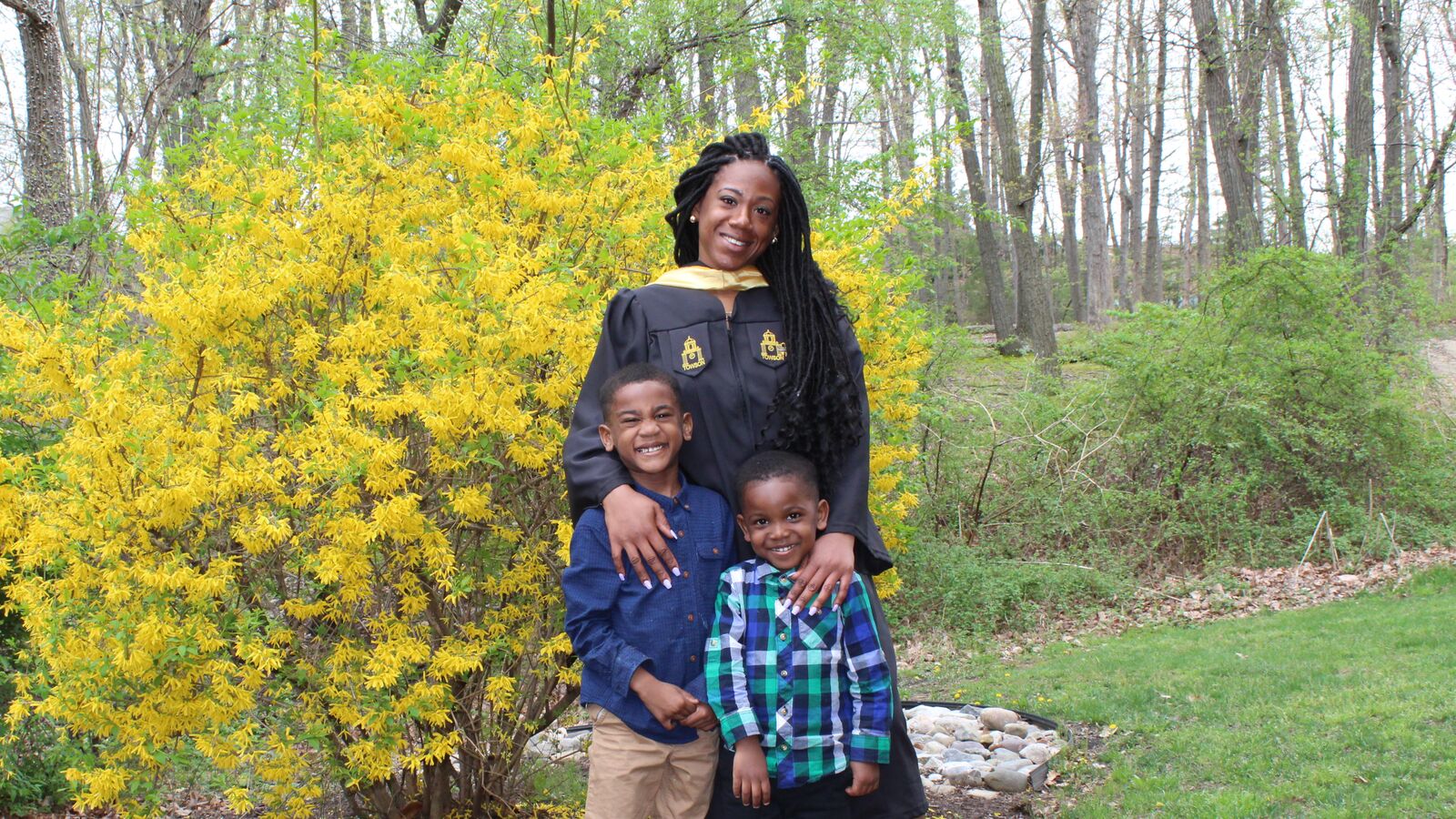 A college graduate supported by Generation Hope poses in cap and gown with her two sons.