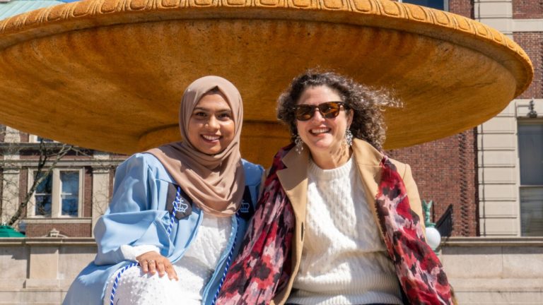 A student and her mentor pose for a photograph in celebration of the student's college graduation.