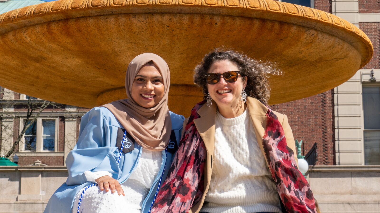 A student and her mentor pose for a photograph in celebration of the student's college graduation.